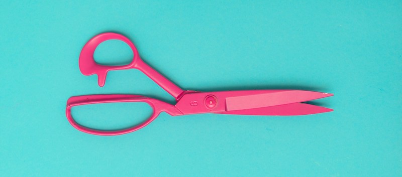 Pink scissors on a turquoise background